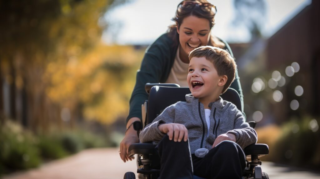 Un petit garçon en situation de handicap se déplace en fauteuil roulant avec sa maman au coucher du soleil.