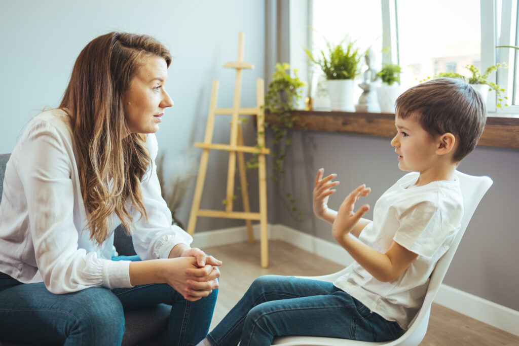 Jeune psychologue accompagnant un enfant lors d’une séance de soutien au développement en répondant à ses questions.