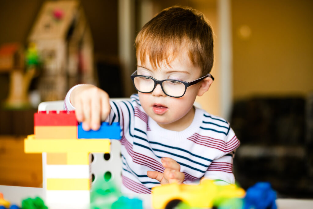 Enfant atteint de trisomie 21 concentré en train de jouer avec des blocs de construction.