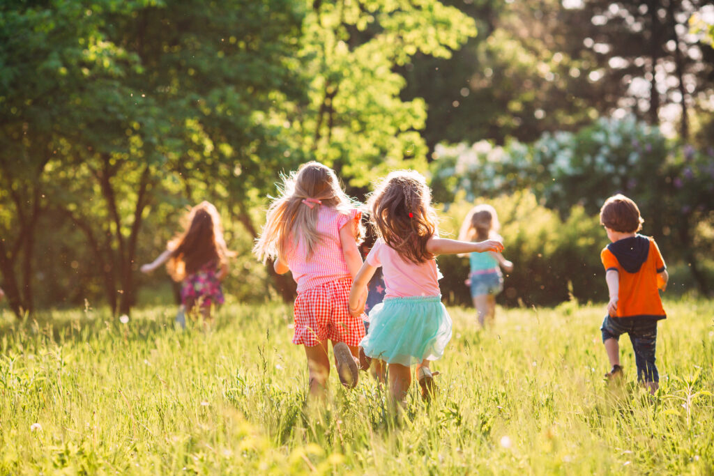 Groupe d’enfants jouant ensemble dans un parc lors d’une activité de jeu extérieur favorisant la socialisation et le développement.