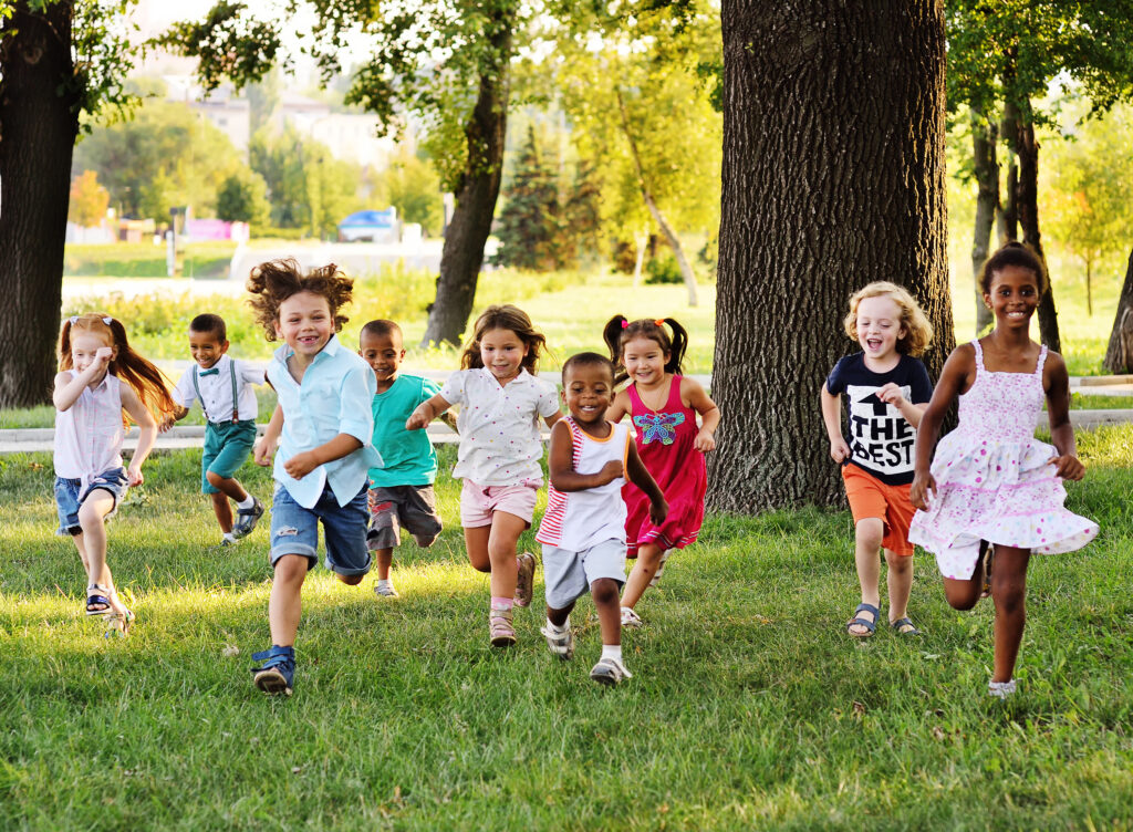 Groupe d’enfants jouant et courant dans un parc en service de garde, favorisant l’intégration et la socialisation
