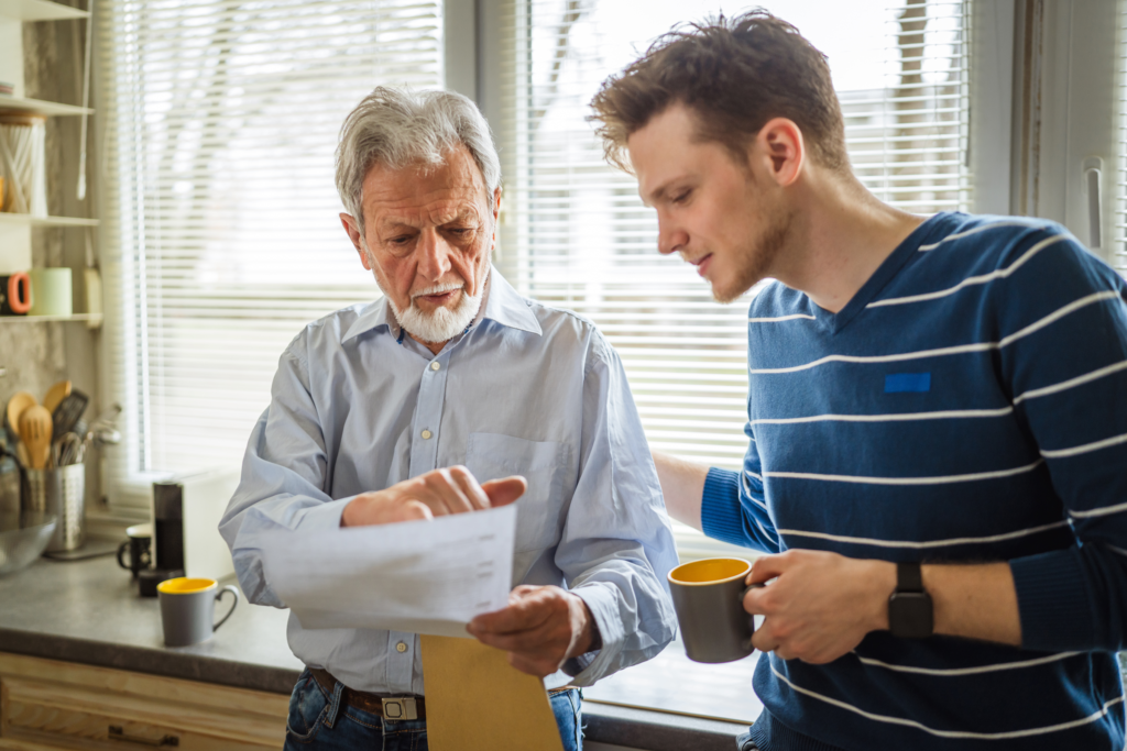 Jeune adulte accompagné d’un proche examinant des documents administratifs, illustrant la gestion des démarches et la transition vers la vie adulte.