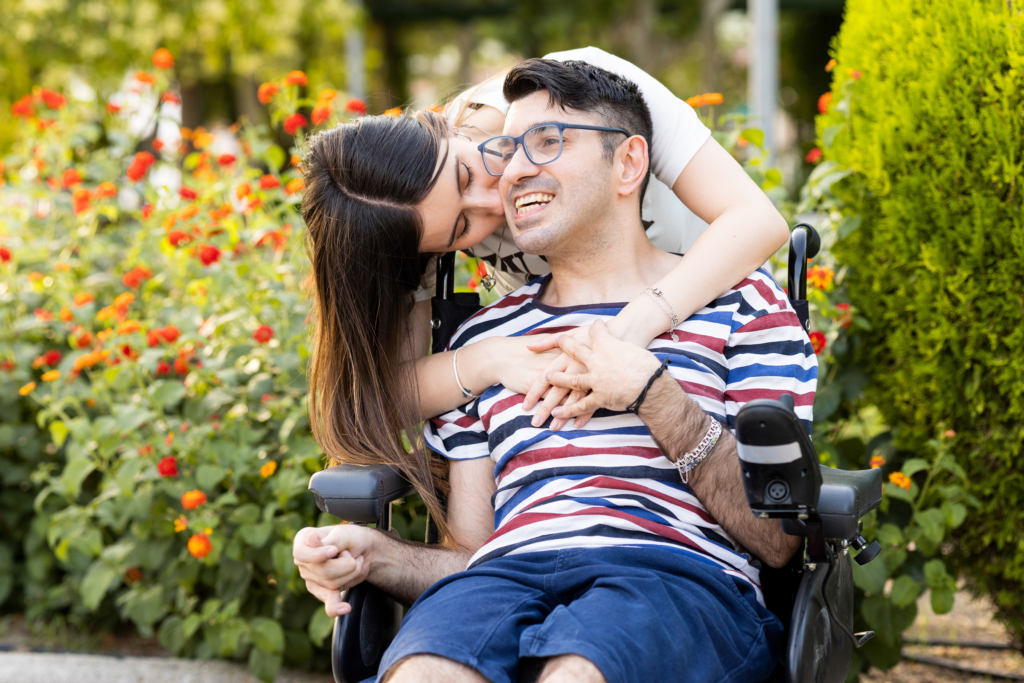 Jeune adulte en fauteuil roulant avec sa petite amie dans un parc, illustrant les relations sociales et affectives en situation de handicap