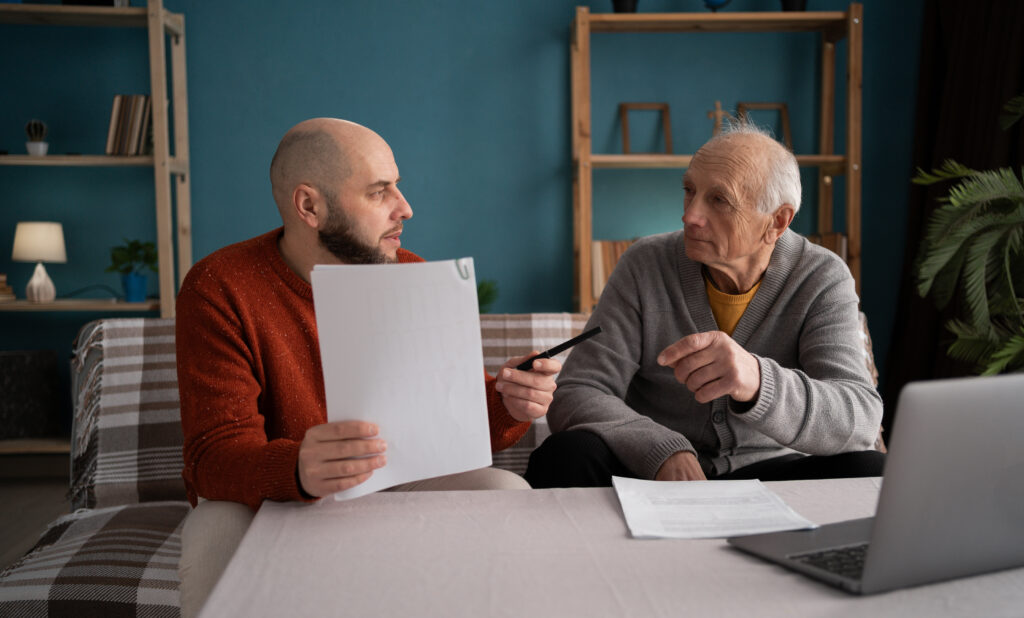 Père et fils adulte examinant des documents à la maison pour planifier l’avenir