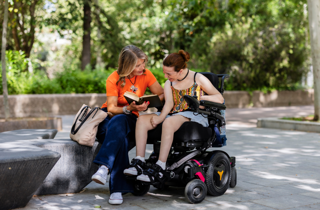 Adulte en situation de handicap et sa mère lisant un livre à l'extérieur